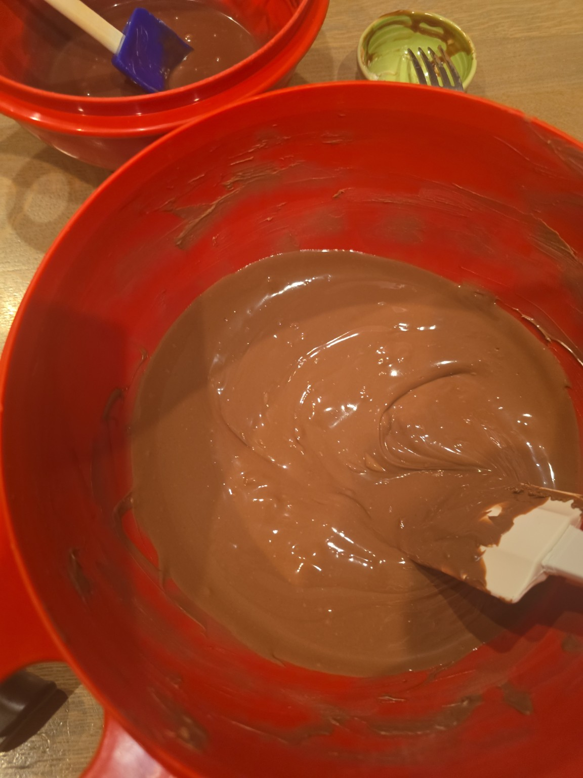 Milk chocolate being stirred in a red mixing bowl